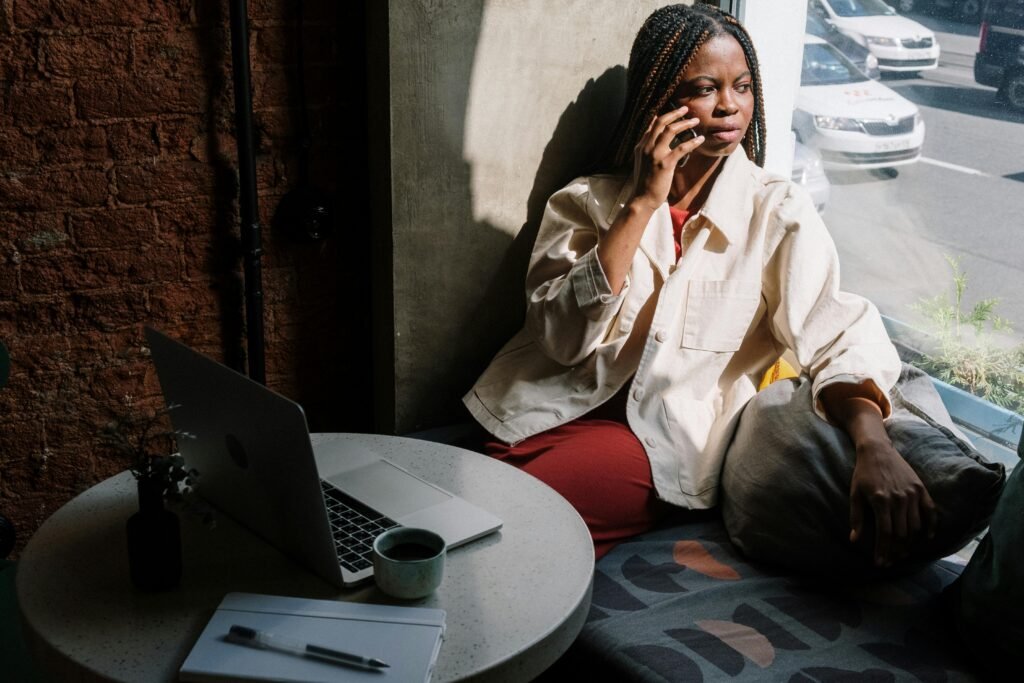 Mulher sentada com celular e computador. Respostas Automáticas no WhatsApp Business – Como Configurar